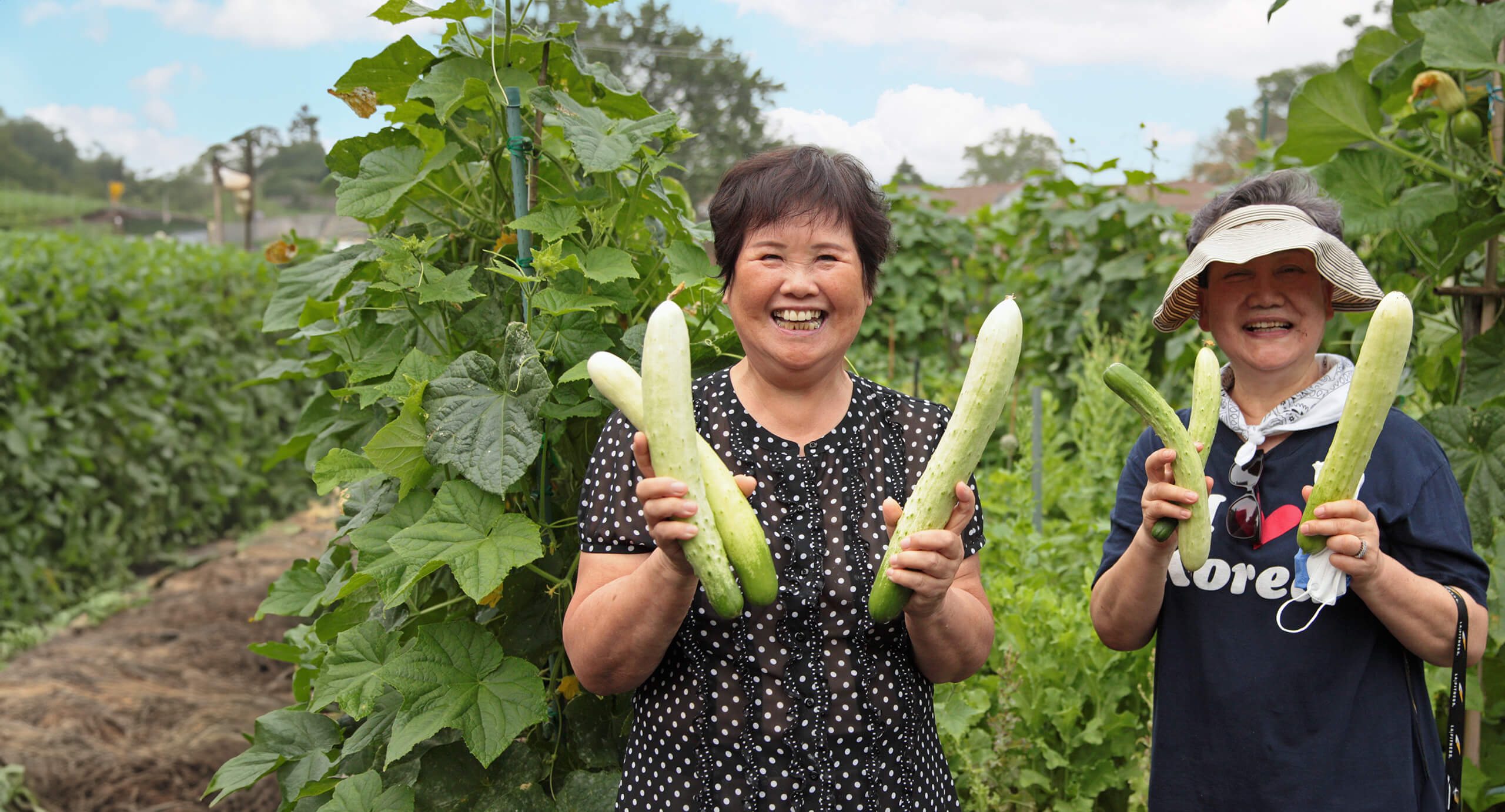 Two women holding vegetables in garden