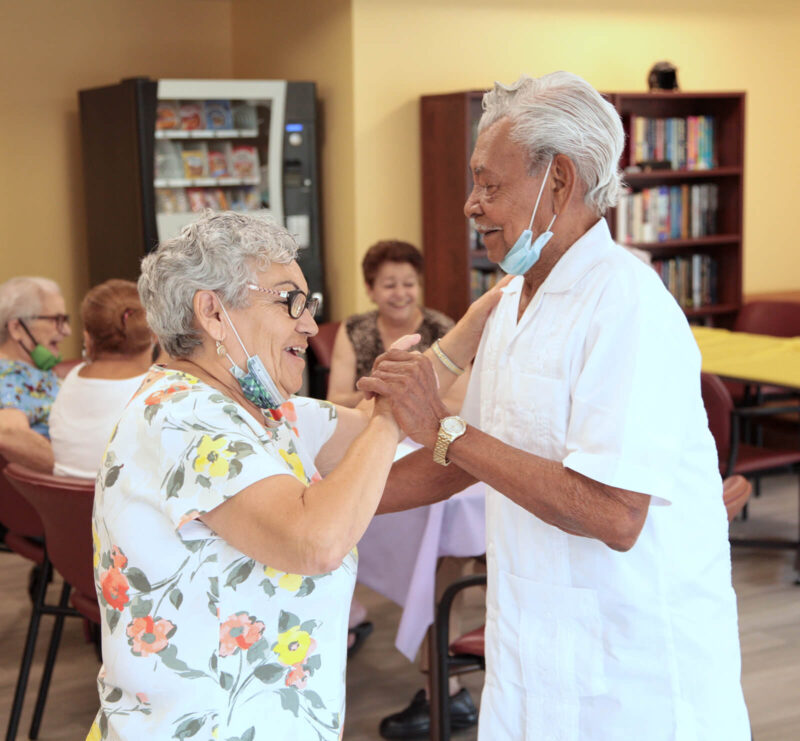 Two elderly residents wearing face masks dancing